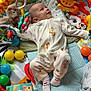 baby, playpen, toys, colorful, blanket, pajamas, socks, animal_print, soft_toys, balls, infant, smiling, cute, child, indoor, playtime, comfort, face, lying_down, happy