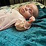 baby, sleeping, blanket, crib, onesie, infant, soft, cute, peaceful, child, closeup, face, hand, pink_clothing, blue_blanket, indoor, portrait, resting, newborn, cozy
