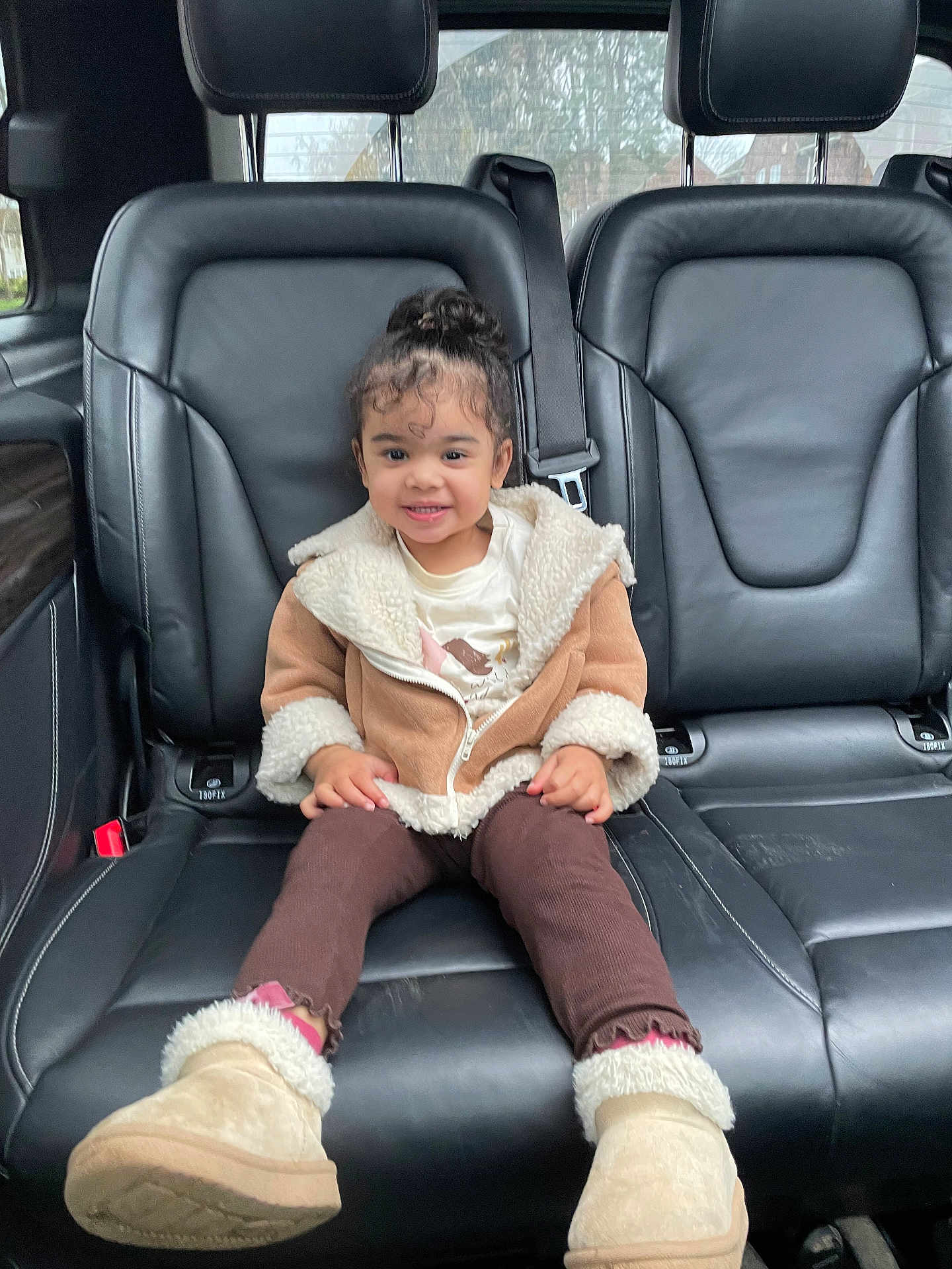 Liyana is registered to the contest to win money with this photo: child, toddler, smile, jacket, boots, car_interior, leather_seat, seatbelt, cute, happy, young_child, clothing, sitting, portrait, indoors, window, hair, face, person, casual