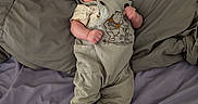Johannah is registered to the contest to win money with this photo: baby, infant, child, lying_down, bed, bedding, blanket, portrait, indoors, clothing, onesie, corduroy, booties, fluffy_shoes, smiling, awake, face, hands, cozy, sleeping_area