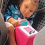 toddler, child, car_seat, toy, pink, denim_jacket, hair_bow, curly_hair, serious_expression, indoor, seat_belt, clothing, hand, face, person, baby, cute, child_safety, transportation, car_interior