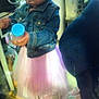 child, denim_jacket, pink_skirt, indoor, toy, person, face, hand, floor, clothing, container, blue_lid, curiosity, standing, casual, young_child, tulle_skirt, home, blurred, focused