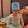 Scarlett is registered to the contest to win money with this photo: toddler, child, bucket_hat, play_mat, toys, book, indoor, curious, kneeling, cartoon_face, colorful, clothing, floor, young_child, expression, playtime, room, learning, cute, baby