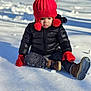 child, toddler, snow, winter_clothing, red_hat, red_mittens, black_jacket, boots, outdoor, cold_weather, sitting, winter, snowy_ground, pom_pom_hat, portrait, cute, young_child, seasonal, daylight, frosty