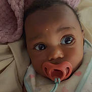 Bella is registered to the contest to win money with this photo: baby, pacifier, blanket, pink, heart_pattern, infant, closeup, face, curious, sleepwear, soft_texture, cozy, indoor, child, portrait, cute, resting, newborn, comfort, warm