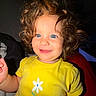 toddler, child, curly_hair, blue_eyes, yellow_shirt, flower_print, smiling, happy, portrait, indoor, baby, person, cute, face, short_sleeves, young_child, bright_colors, innocence, playful, closeup