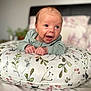 baby, infant, pillow, floral_pattern, bedroom, smiling, person, cute, happy, child, clothing, bed, head, face, hands, indoors, soft_focus, expression, lying_down, cozy