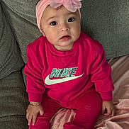 Jaylah is registered to the contest to win money with this photo: baby, child, pink_clothing, headband, flower, nike_logo, sitting, couch, blanket, indoors, cute, portrait, happy, face, braclet, socks, apparel, infant, fashion, cozy