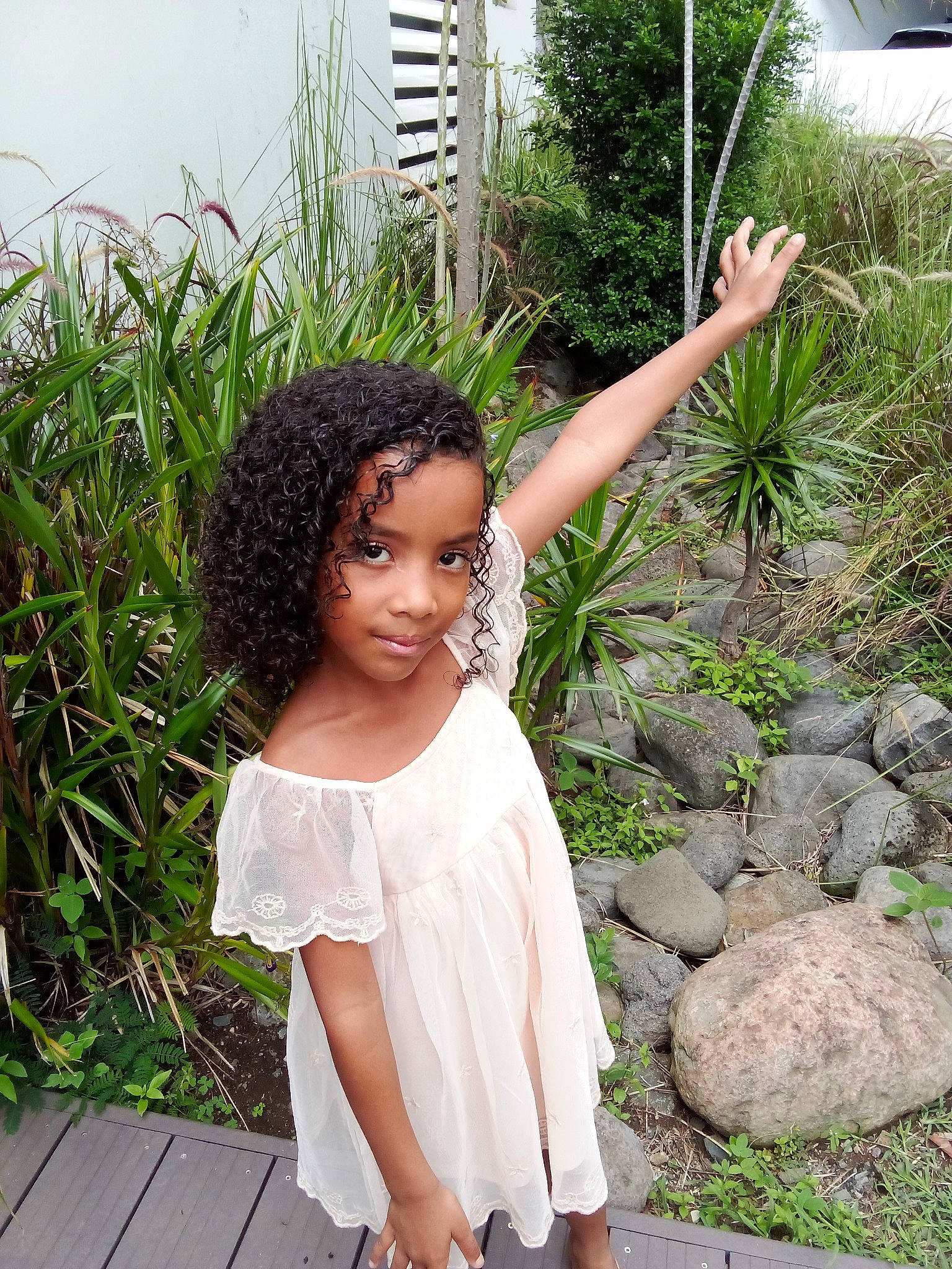 Nailys participe au concours pour gagner de l'argent avec cette photo : black_hair, child, day_dress, fashion_accessory, formal_wear, garden, grass, happy, human_body, joint, leisure, long_hair, pattern, people_in_nature, person, plant, shrub, sitting, summer, terrestrial_plant