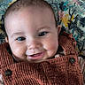 apparel, baby, bright_eyes, button, cheeks, child, closeup, clothing, corduroy, cute, face, happy, head, indoor, infant, patterned_background, portrait, sitting, smiling, young