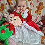 Emilia-Rose is registered to the contest to win money with this photo: baby, infant, plush_toy, elf, christmas, holiday, festive_clothing, red_dress, white_fur_trim, gingerbread_men, candy_canes, blanket, cute, smiling, indoors, child, soft_toy, celebration, happy, holiday_theme