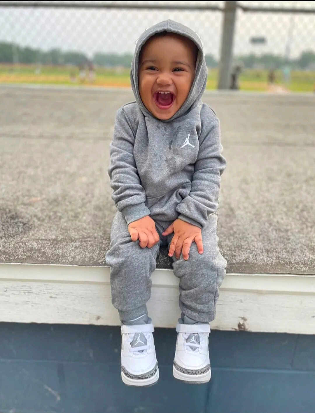 Nicolas joined the competition — help win amazing prizes! toddler, child, smiling, laughing, hoodie, sweatpants, sneakers, grey_clothing, outdoor, bench, happy, casual, young_child, sitting, joyful, person, footwear, urban, daytime, portrait