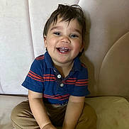 Toviyah joined the competition — help win amazing prizes! toddler, child, smile, happy, sitting, blue_shirt, striped_clothing, khaki_pants, indoor, couch, furniture, face, person, cute, young_child, hands, hair, portrait, casual, playful