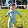 Toviyah is registered to the contest to win money with this photo: toddler, child, barefoot, grass, outdoor, sunny, daylight, blue_sweater, pants, baby, walking, greenery, trees, blurred_background, smiling, young_child, playful, casual_clothing, nature, park