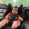 Toviyah is registered to the contest to win money with this photo: baby, child, car_seat, orange_shirt, car_interior, seatbelt, mohaawk_hairstyle, barefoot, curious_face, rear_window, greenery, leather_seat, strapped_in, infant, car_trip, safety, cute, portrait, young_child, indoors