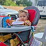Leyna a rejoint le concours — aidez-le/la à gagner de superbes lots ! baby, child, high_chair, headband, toy, outdoor, plastic_chair, red, gray, yellow, curious, infant, seated, clothing, play, face, person, reaching, background, daylight