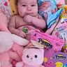 baby, child, blanket, plush_toy, pink, candy, peeps, stuffed_animal, cute, indoor, portrait, smiling, toddler, soft_toys, colorful, face, hand, comfort, playful, cozy