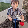 Ben is registered to the contest to win money with this photo: child, boy, scooter, crocheted_toy, bunny, plaid_shirt, sneakers, sidewalk, suburban, neighborhood, grass, shrub, porch, outdoor, daylight, casual_clothing, smiling, curious, young, person