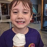 Ben is registered to the contest to win money with this photo: child, boy, ice_cream, cone, smile, gap_tooth, purple_shirt, indoor, restaurant, table, casual, happy, food, dessert, hand, face, person, hair, sitting, young