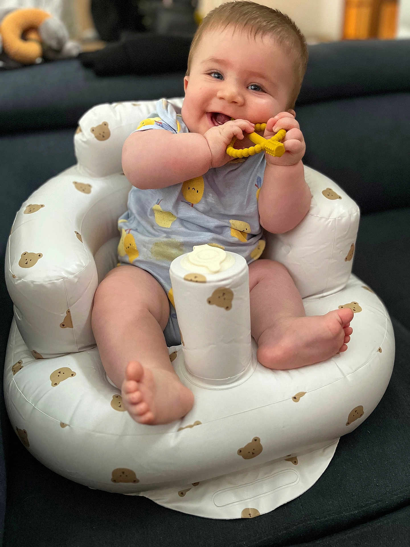Maël a rejoint le concours — aidez-le/la à gagner de superbes lots ! baby, infant, smiling, teething_toy, inflatable_chair, teddy_bear_pattern, blue_onesie, sitting, happy, cute, child, indoor, plush, foot, hand, face, cheeks, toy, relaxing, comfort