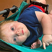 Noah is registered to the contest to win money with this photo: baby, blue_eyes, blue_shirt, candid, casual, child, closeup, curious, face, foot, hand, indoor, infant, portrait, red_shorts, relaxed, seated, skin, stroller, toddler
