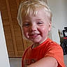 child, boy, toddler, smiling, happy, portrait, indoor, toy, toy_truck, orange_shirt, blond_hair, blue_eyes, face, hand, arm, home, shutters, furniture, closeup, playtime