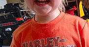 Tyler joined the competition — help win amazing prizes! child, toddler, smiling, laughing, portrait, indoors, orange_shirt, harley_davidson, blond_hair, blue_eyes, face, teeth, happy, standing, home, furniture, shelf, toys, denim, photography
