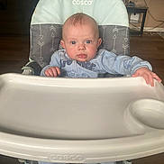 Elijah joined the competition — help win amazing prizes! baby, high_chair, infant, blue_eyes, cosco, clothing, onesie, hand, face, indoor, floor, wooden_floor, table, living_room, furniture, person, child, curious, seated, portrait