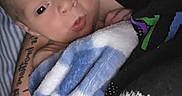 Theodore joined the competition — help win amazing prizes! baby, blanket, arm, tattoo, person, infant, closeup, portrait, skin, holding, comfort, indoor, warmth, soft, sleepwear, newborn, face, hand, cuddle, resting