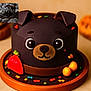 dog_cake, black_dog, puppy, cake, dessert, chocolate, cute, decorations, colorful, plate, food, sweet, animal_shape, toy, blanket, clothing, small_dog, indoor, closeup, pet