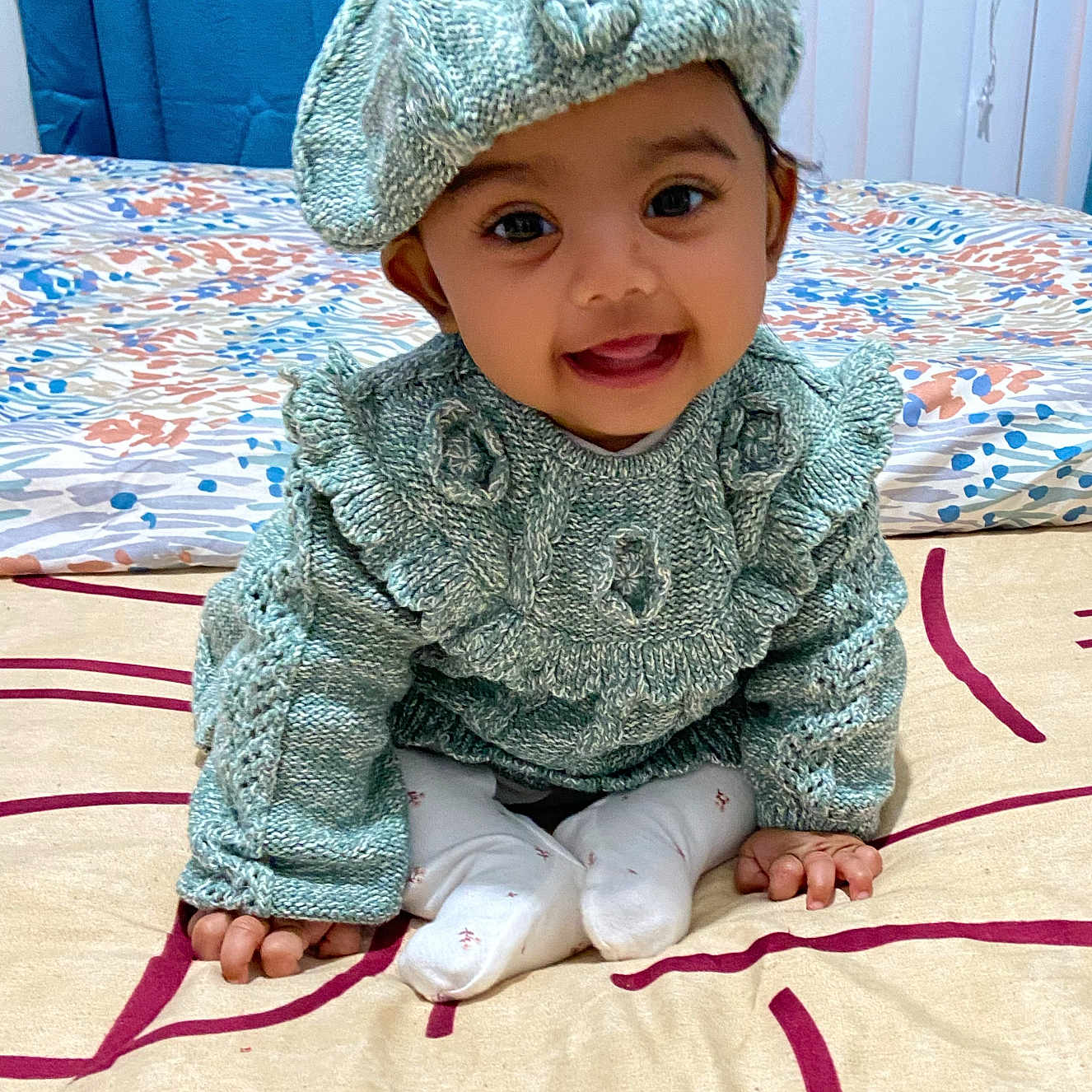 Aaira Ghosh is registered to the contest to win money with this photo: baby, bed, beret, blanket, child, cozy, cute, fabric, hands, happy, home, indoor, infant, knitted_clothing, patterned, person, portrait, sitting, smiling, warm_clothes