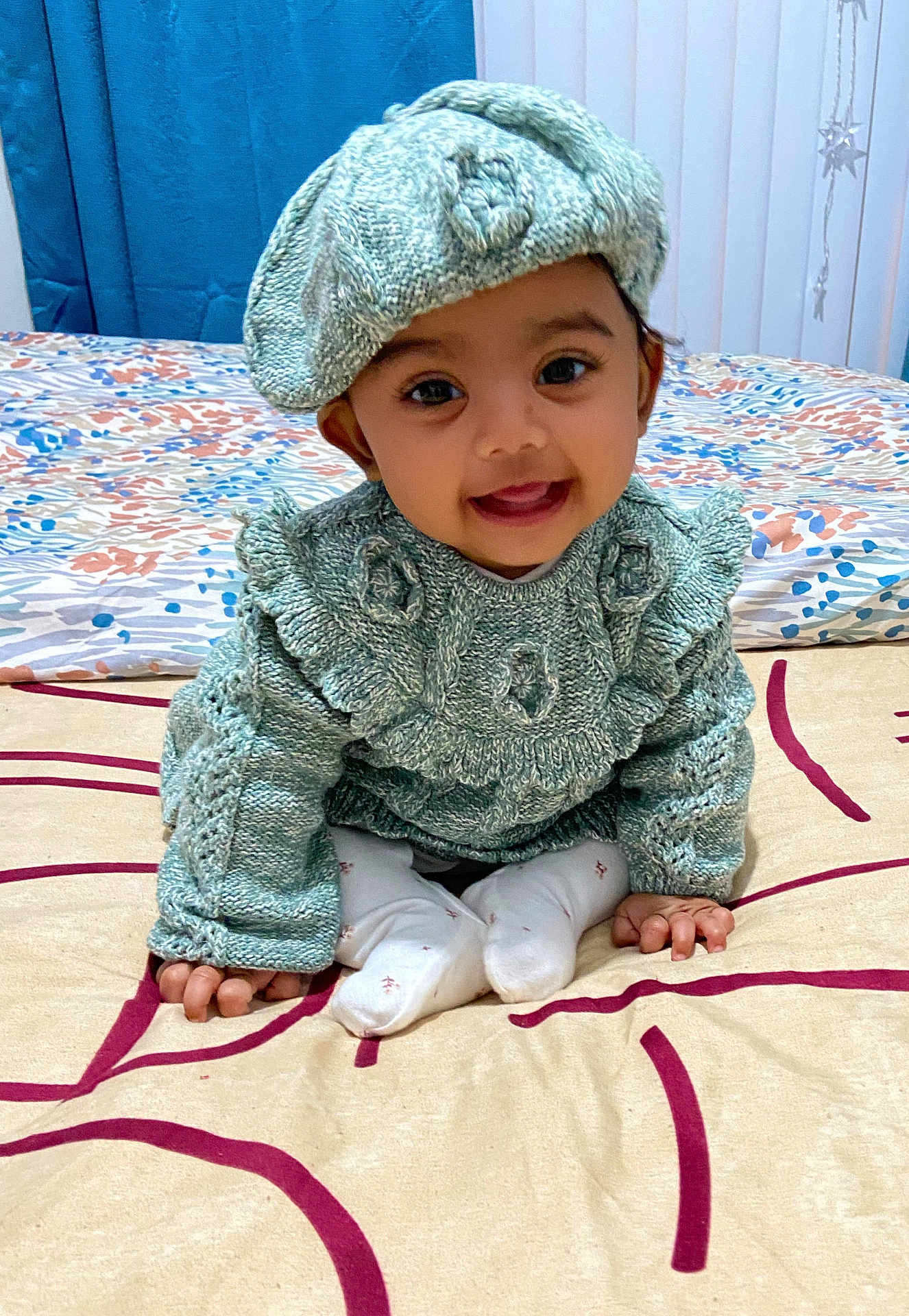 Aaira Ghosh is registered to the contest to win money with this photo: baby, bed, beret, blanket, child, cozy, cute, fabric, hands, happy, home, indoor, infant, knitted_clothing, patterned, person, portrait, sitting, smiling, warm_clothes