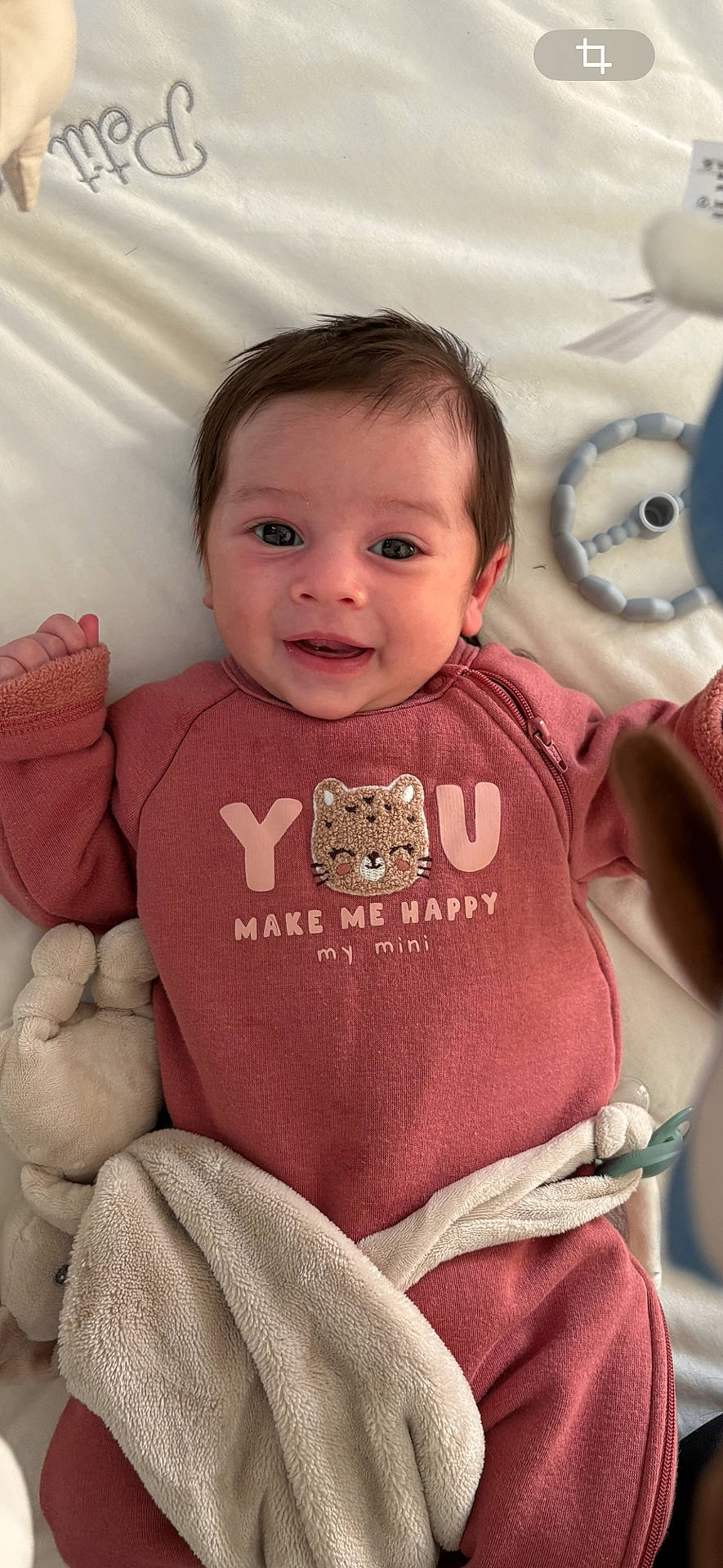 baby, blanket, cat_design, child, closeup, comfortable, cozy, cute, face, happy, indoors, infant, lying_down, pacifier, pink_clothing, plush_toy, portrait, smiling, soft_texture, young_child