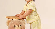 Eithan Milan is registered to the contest to win money with this photo: child, childhood, curly_hair, cute, happy, indoor, innocence, person, playful, plush_toy, portrait, smiling, soft_lighting, standing, striped_clothing, studio_background, teddy_bear, toddler, wooden_stool, yellow_outfit