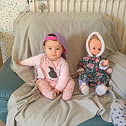 Joumana participe au concours pour gagner de l'argent avec cette photo : baby, blanket, cap, chair, child, cute, doll, expressionless, floral_coat, footwear, furniture, home, hood, indoor, person, pink_clothing, sitting, toddler, toy, wallpaper