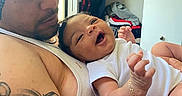Amelia is registered to the contest to win money with this photo: baby, bracelet, closet, clothing, family, furniture, hair, hanger, happy, holding, indoors, love, man, onesie, person, portrait, room, skin, smiling, tattoo