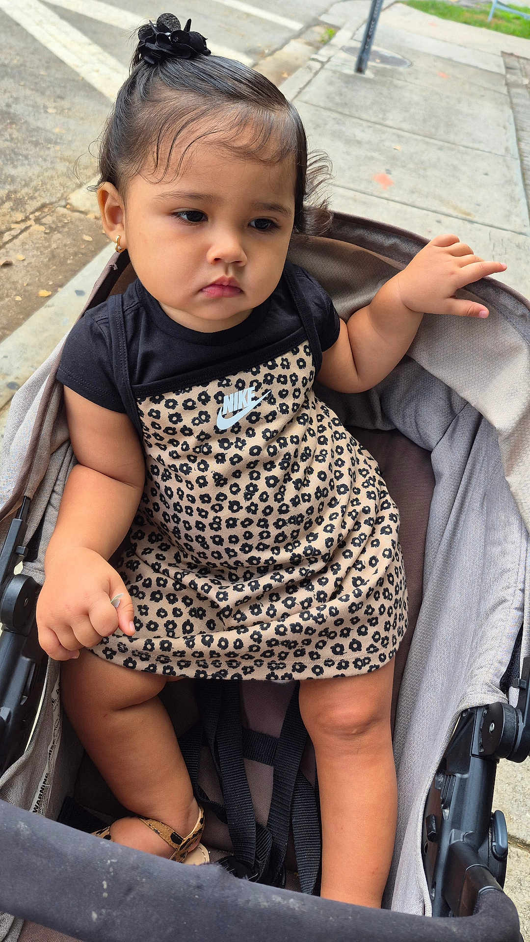 Isabella joined the competition — help win amazing prizes! toddler, child, stroller, dress, nike, black_hair_accessory, leopard_print, sandals, sidewalk, urban, outdoor, person, footwear, clothing, expression, hair, sitting, cute, fashion, baby