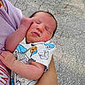 newborn, baby, infant, person, sleeping, cute, onesie, milk_carton, blue, hand, arm, skin, outdoor, pavement, holding, peaceful, face, closed_eyes, small_fist, clothing