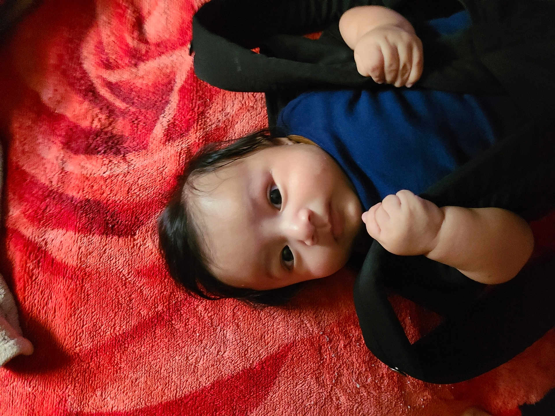 William joined the competition — help win amazing prizes! baby, infant, child, face, hands, clothing, blanket, red, black, pattern, lying_down, portrait, cute, soft, skin, hair, expression, indoor, cozy, curious