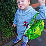 child, boy, outdoor, ivy, sidewalk, concrete, bag, avengers, spiderman, tracksuit, sneakers, pointing, green, playful, casual, smile, urban, young, person, daytime