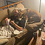 Blainn is registered to the contest to win money with this photo: man, dog, couch, drink, glasses, tattoo, blanket, pillow, table, can, lamp, wooden_table, living_room, relaxing, indoor, pet, casual, beverage, comfort, friendship