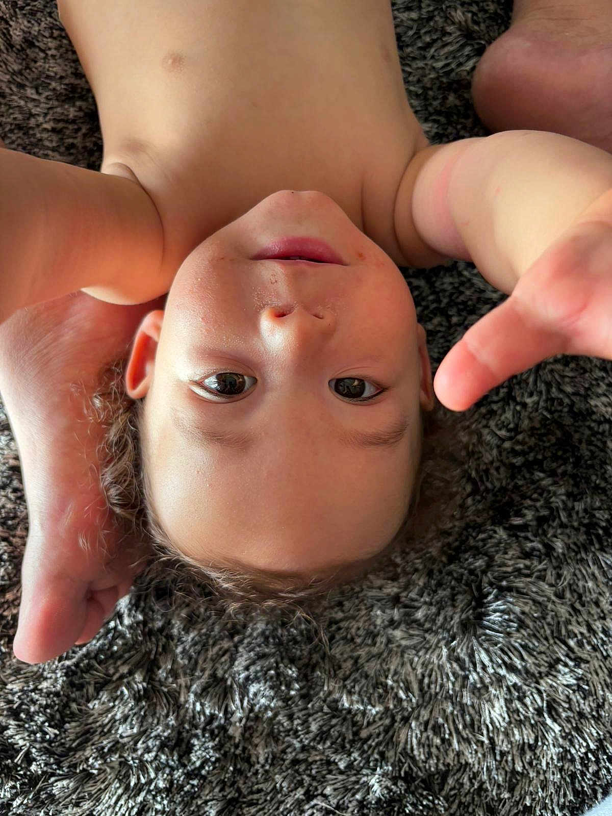 Maho a rejoint le concours — aidez-le/la à gagner de superbes lots ! toddler, child, upside_down, carpet, foot, skin, playful, reaching_hand, curly_hair, close_up, indoor, person, young_child, face, expression, bare_chest, texture, casual, relaxed, home