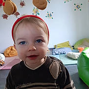 Ethan a rejoint le concours — aidez-le/la à gagner de superbes lots ! blue_eyes, child, colorful, cozy, cushions, cute, face, festive, holiday_theme, indoor, person, playroom, reindeer_headband, short_hair, smiling, soft_lighting, striped_sweater, toddler, wall_decorations, young_child