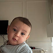 Zayn participe au concours pour gagner de l'argent avec cette photo : baby, candid, child, curious, curtain, expression, face, head, indoor, light_clothing, long_sleeve, looking_at_camera, person, portrait, radiator, skin, television, wall, window, young_child