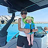 Jensen joined the competition — help win amazing prizes! baby, child, adult, mother, boat, speedboat, life_jacket, sun_hat, sunglasses, smiling, outdoor, water, lake, shoreline, summer, sunny, family, portrait, maritime, recreation