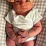 baby, infant, headband, bow, white_onesie, pillow, checkered_pattern, hands, legs, skin, face, eyes, indoor, newborn, cute, resting, clothing, soft_light, portrait, child
