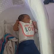 Jalae is registered to the contest to win money with this photo: baby, newborn, sleeping, bassinet, pacifier, bib, blanket, clothing, infant, resting, indoors, white, blue, text, peaceful, cute, soft, child, bed, comfort