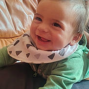 Elyan a rejoint le concours — aidez-le/la à gagner de superbes lots ! baby, smiling, green_clothing, bib, face, infant, happy, cute, child, indoor, couch, leather, portrait, young_child, skin, hand, sleeve, head, eyes, mouth