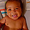 baby, infant, child, smiling, happy, portrait, close_up, curly_hair, brown_skin, lying_down, diaper, changing_table, cartoon_background, colorful, indoor, face, eyes, open_mouth, text_overlay, emojis