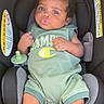baby, infant, child, car_seat, portrait, smiling, kissy_face, curly_hair, green_outfit, romper, pacifier, vehicle, seated, indoors, close_up, safe, happy, face, fashion, photography
